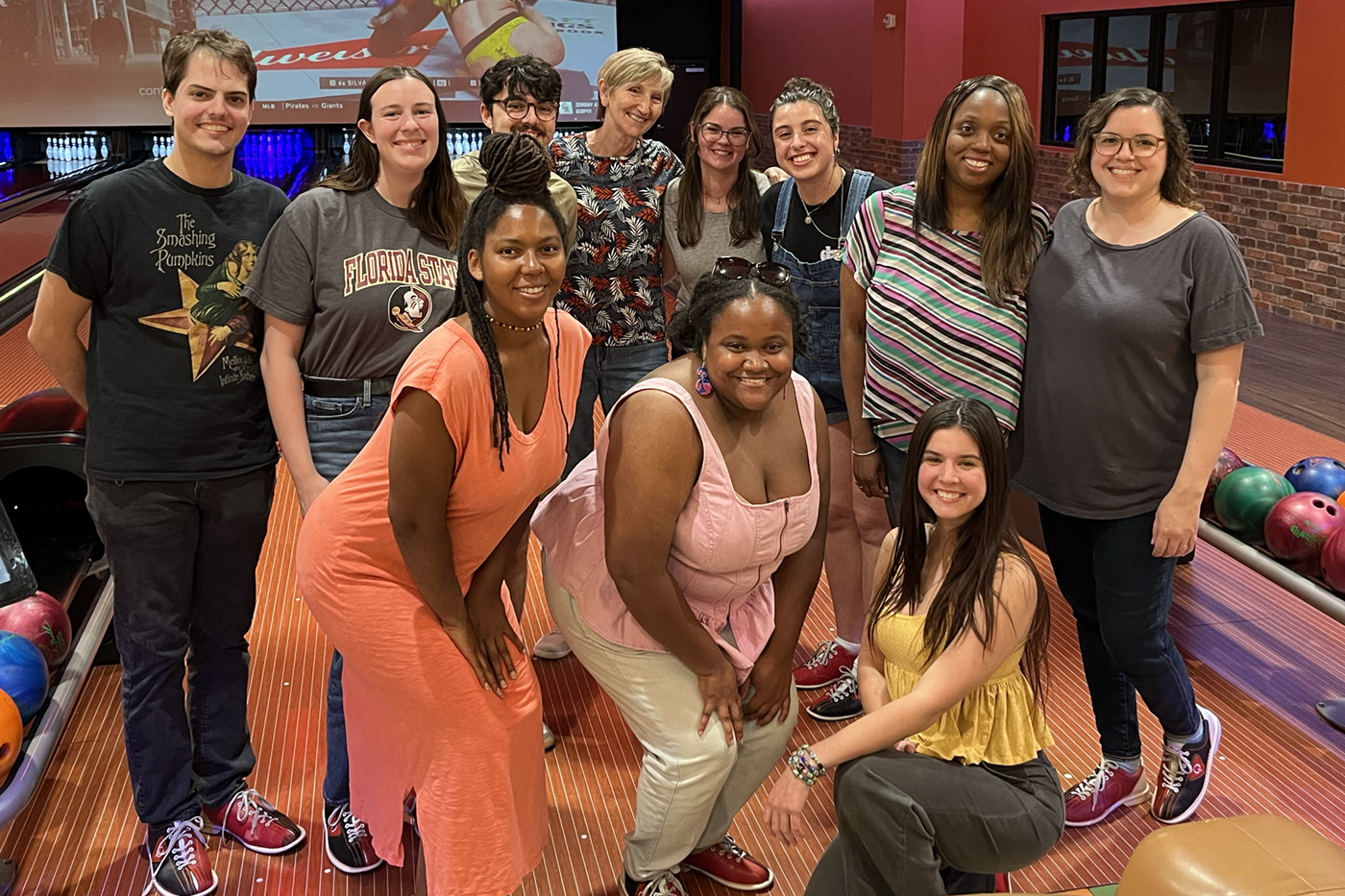 a group of people posing for a photo in a bowling alley