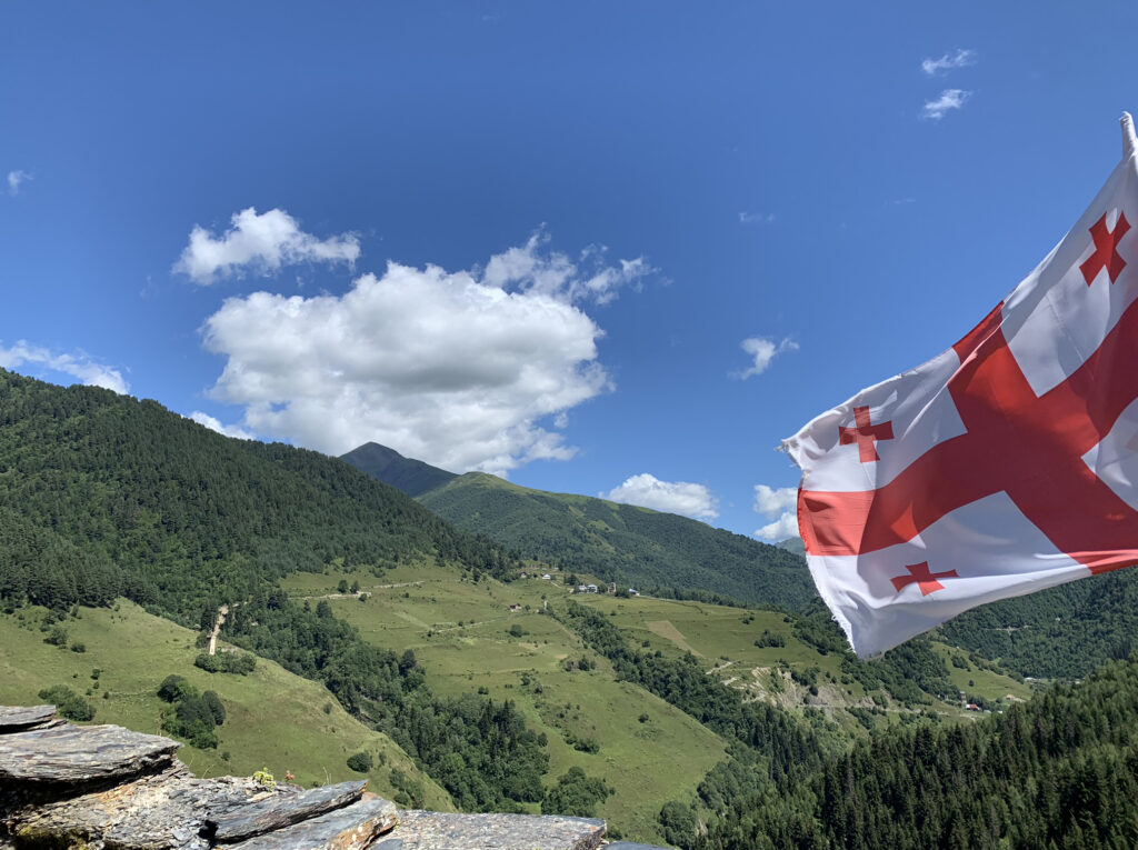 there is a flag that is flying in the air on top of a hill