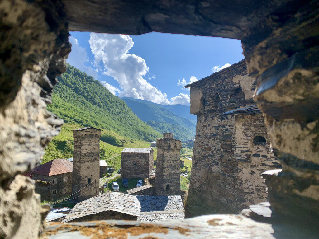 there is a view of a small town through a hole in a stone wall