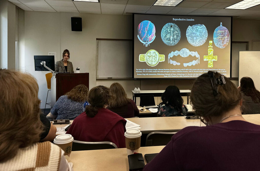 there is a woman giving a presentation in front of a room full of people