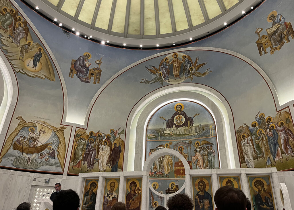 there is a group of people standing in front of a wall with paintings on it