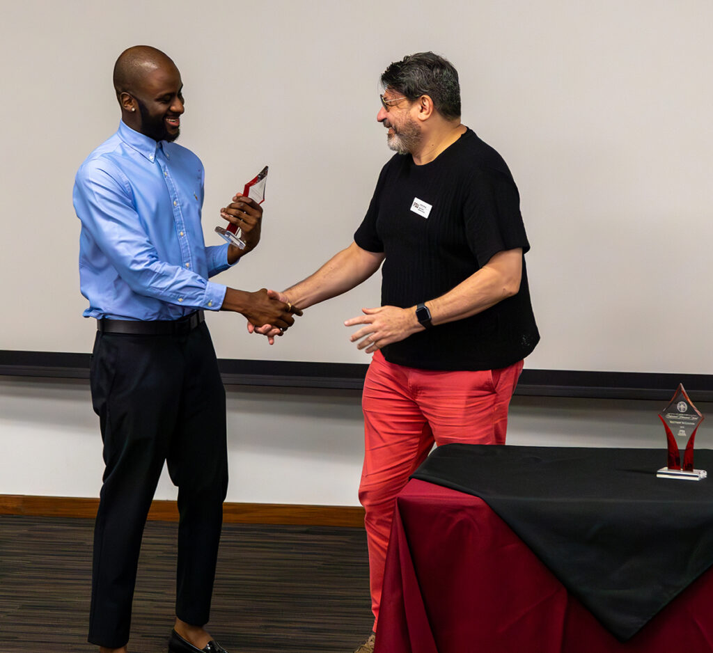 there are two men shaking hands in front of a table with a red table cloth