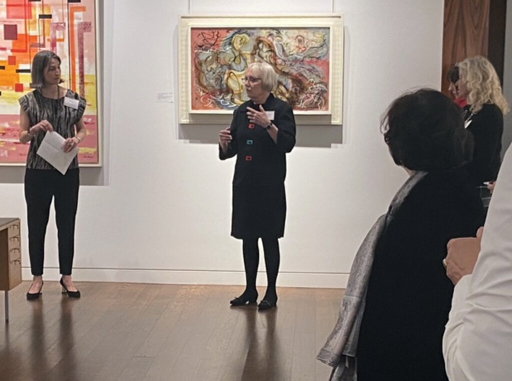 there is a woman standing in front of a group of people in an art gallery