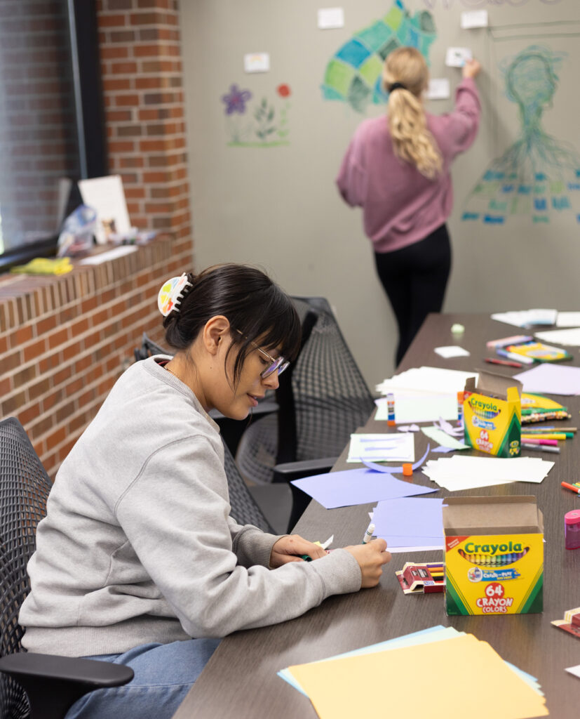 there is a woman sitting at a table writing on a piece of paper