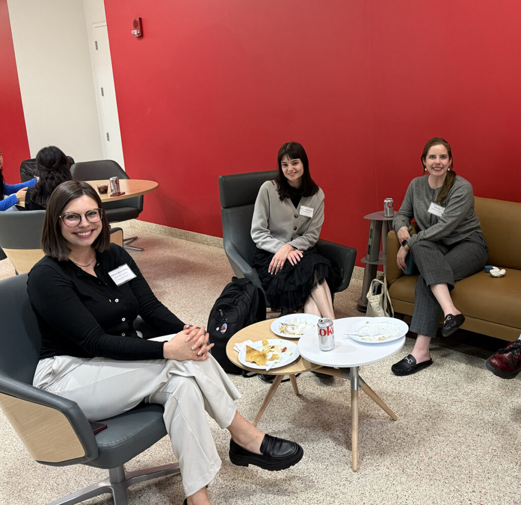 three women sitting in chairs in a room with a red wall