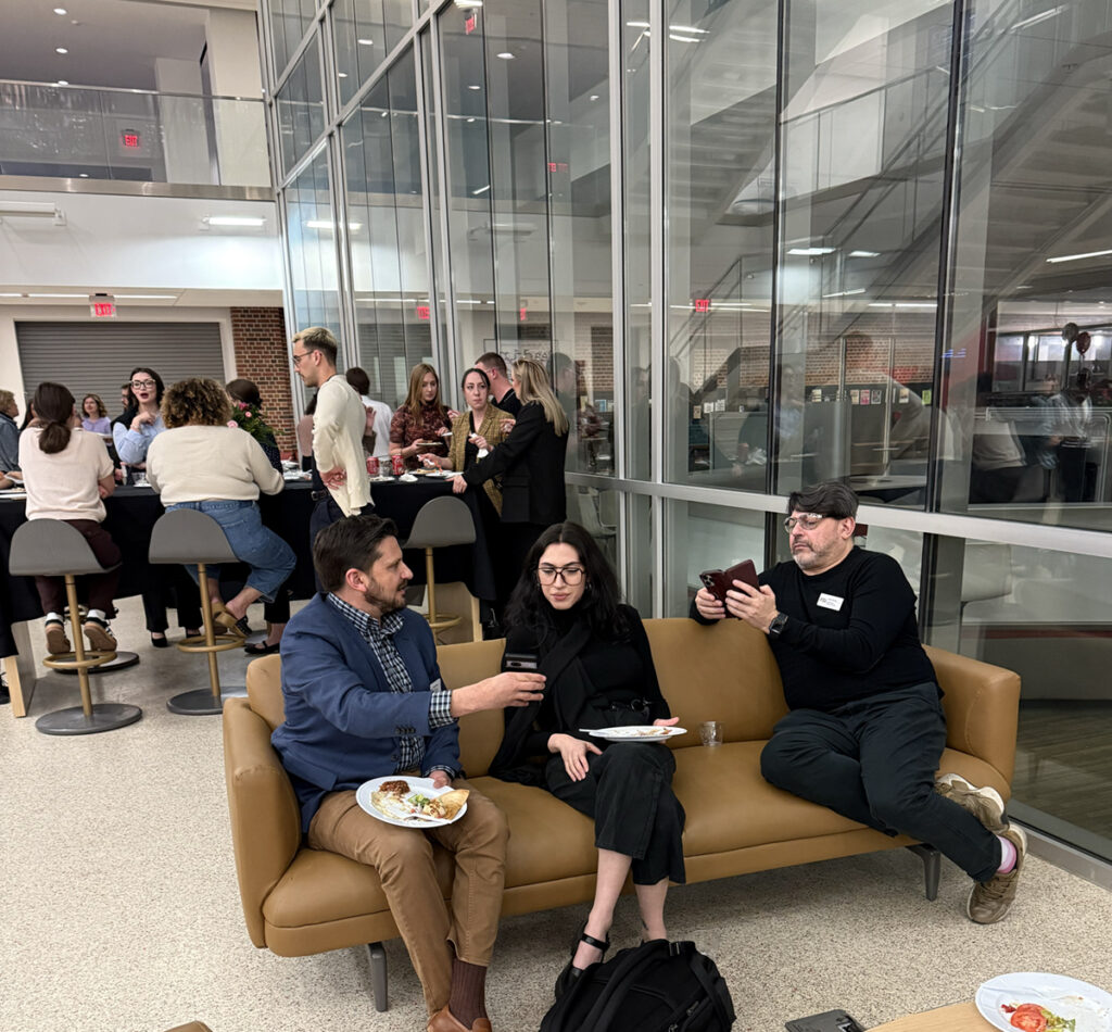several people sitting on a couch in a lobby eating and drinking