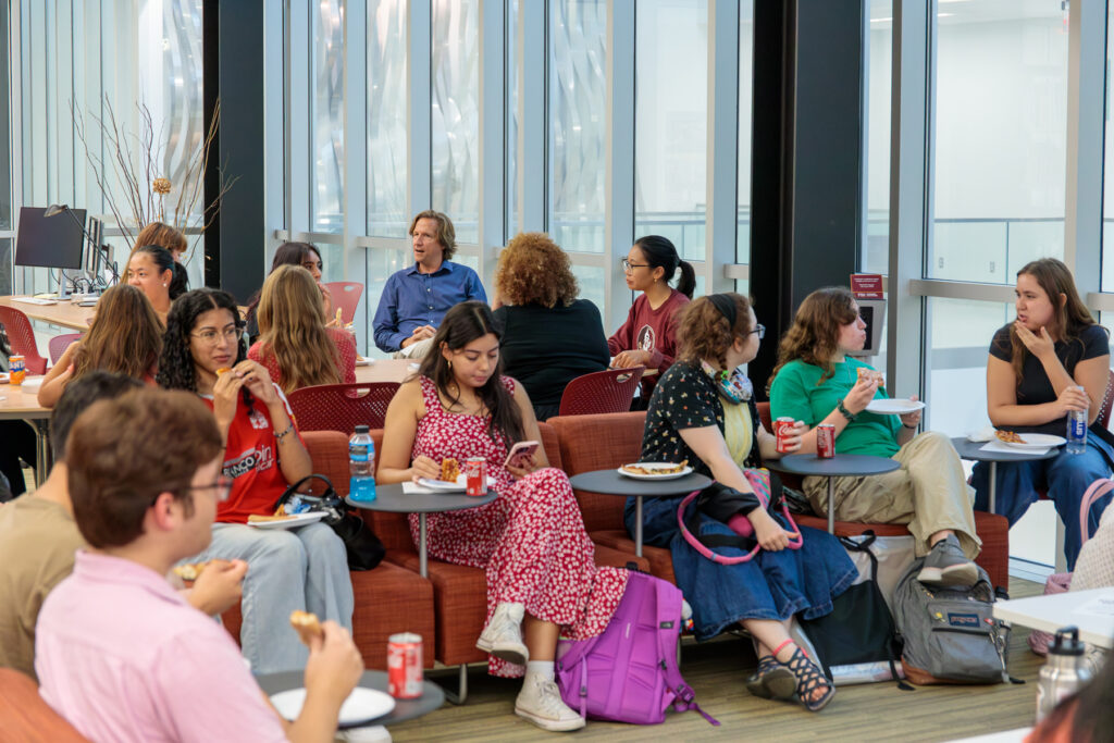 there are many people sitting in a room eating and drinking