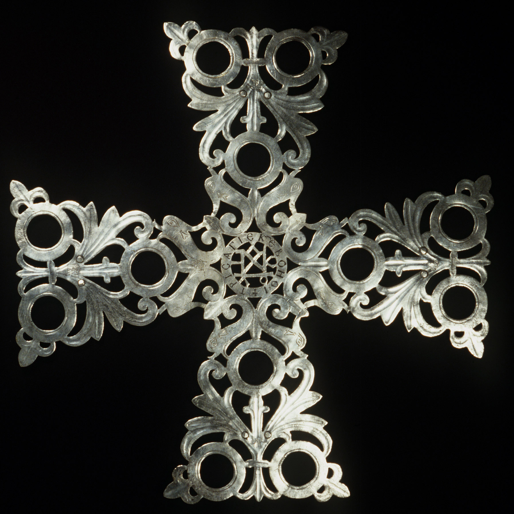 there is a cross made out of silver metal on a black background