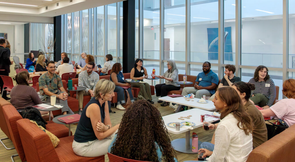 there are many people sitting at tables in a large room