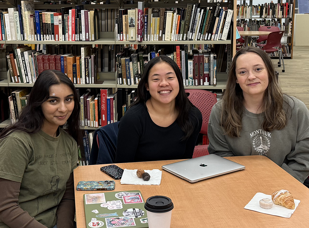 there are three women sitting at a table with a laptop in front of them