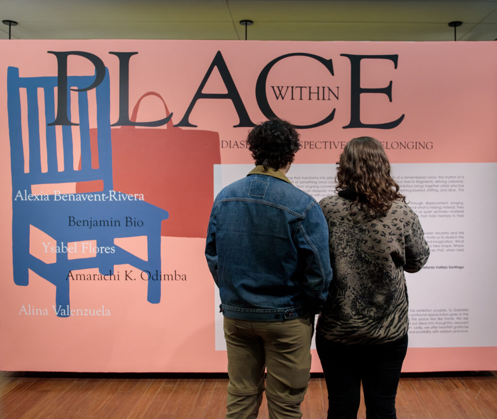 there are two people standing in front of a wall with a chair on it