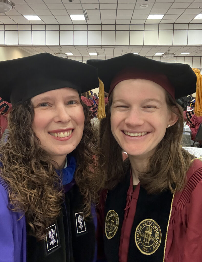 there are two women wearing caps and gowns posing for a picture