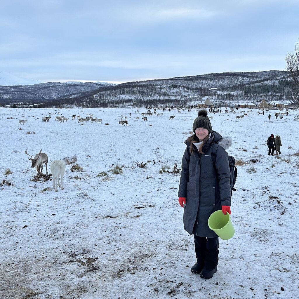 there is a woman that is standing in the snow with a frisbee
