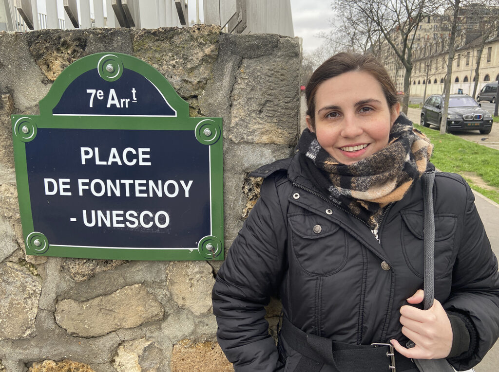 there is a woman standing in front of a sign that says place de fontenoy unescosco