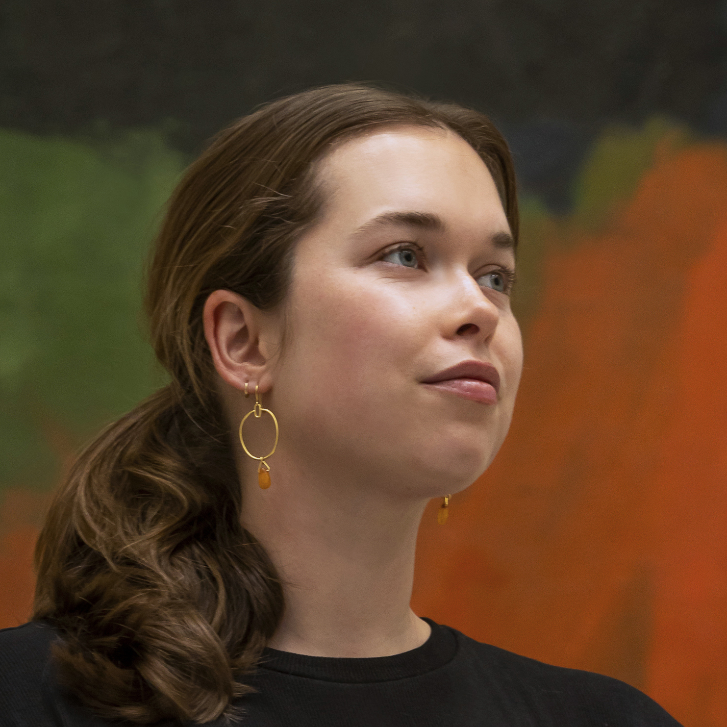 there is a woman standing in front of a painting with a cell phone in her hand