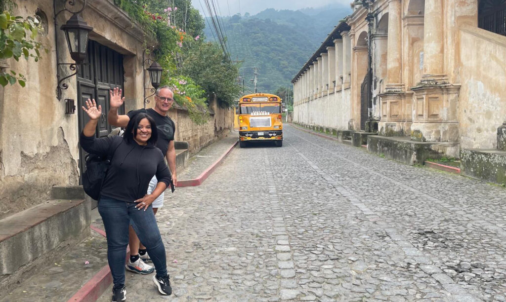 there is a man and a woman standing in front of a school bus