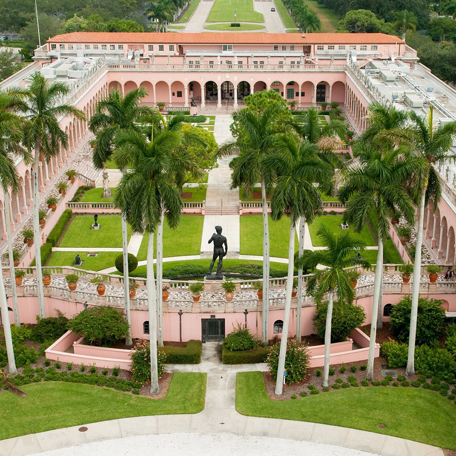 this is an aerial view of a pink building with palm trees in front of it