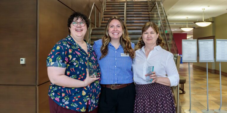 Three women in professional attire pose for a photo