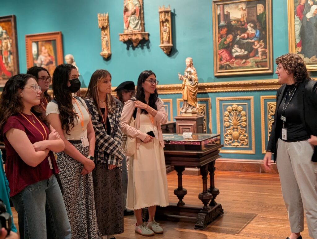 A group on a museum tour in a brightly colored room full of baroque art. 