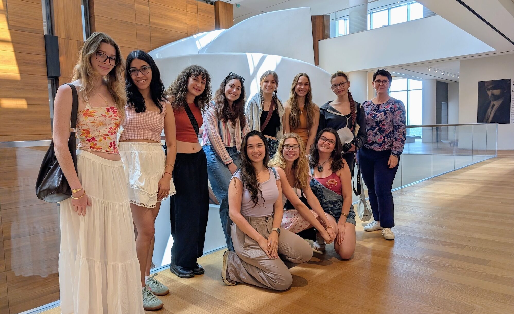 A group of women pose in a bright sunny room with wood floors